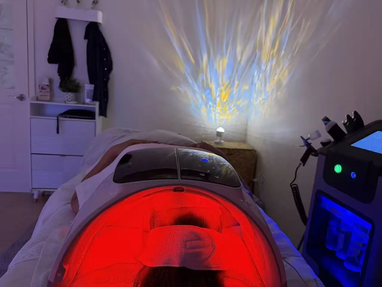 Guest receiving LED red-light therapy on a treatment bed with ambient light projection at Jinyue Head Spa in Flushing